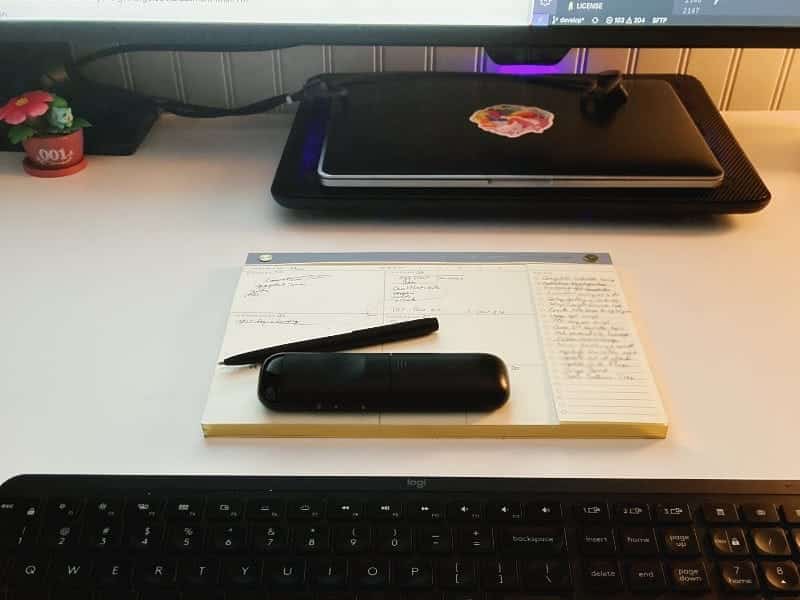 A desk calendar and to-do list in front of a laptop and behind a keyboard