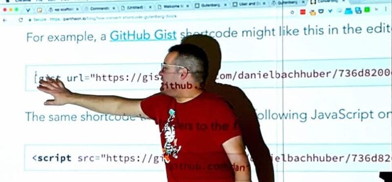 david standing in front of a projector screen showing some code from Github